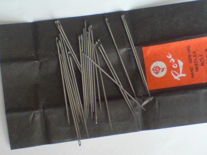 May include: A pack of silver sewing needles labeled "Rose Hand Sewing Needles No. 1" on a black background.