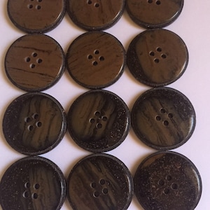 May include: Twelve brown buttons with four holes each. The buttons have a wood grain pattern and a dark brown border.