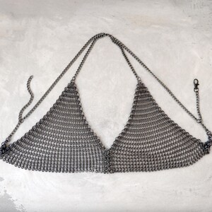 May include: A silver chainmail top with a triangular shape and adjustable straps.