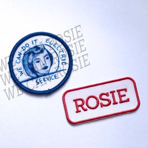 May include: Two embroidered patches. One is round and blue with a white background and a woman's face in the center. The text reads "We Can Do It Electric Service". The other patch is rectangular and white with a red border and the text "Rosie" in red.