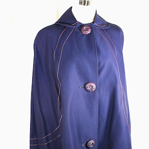 Capa azul marino para mujer Town N Country estilo años 60. Cierre frontal con botones grandes. Aberturas en los brazos con forma de media luna. Detalles de doble costura. Talla única.
