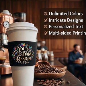 May include: A white coffee cup with a black sleeve featuring a colourful graphic with the text "YOUR CUSTOM DESIGN" and a heart icon. To the right, a dark brown sign lists features: Unlimited Colours, Intricate Designs, Personalised Text, Multi-sided Printing.
