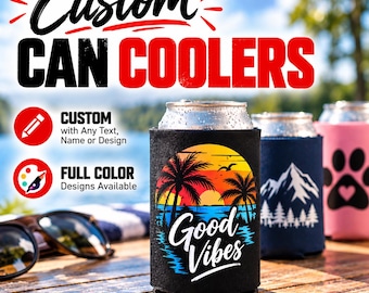 May include: Three cylindrical foam can coolers in black, navy blue, and pink. The black cooler features a sunset, palm trees, and the text "Good Vibes". The navy cooler shows a white mountain range, and the pink cooler displays a black paw print.