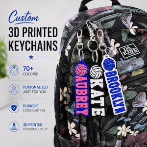 Puede incluir: Tres llaveros personalizados impresos en 3D sujetos a una mochila con estampado floral. Cada llavero muestra un icono de voleibol sobre un nombre: AUBREY en rosa sobre azul, KATE en blanco sobre negro y BROOKLYN en azul sobre blanco. Texto: 3D PRINTED KEYCHAINS.