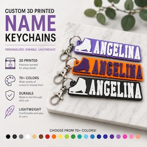 Op de afbeelding: Drie 3D-geprinte rechthoekige sleutelhangers met zilverkleurige metalen karabijnsluitingen. Elke sleutelhanger toont een wit silhouet van een schaats en de naam ANGELINA in dikke witte letters. De basiskleuren zijn paars, oranje en zwart.