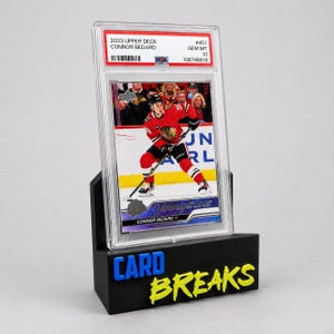 May include: A 2023 Upper Deck Connor Bedard hockey trading card graded Gem Mt 10 by PSA, encased in a clear plastic slab. The card features a player in a red jersey on ice. It is displayed on a black stand with blue and yellow text reading CARD BREAKS.