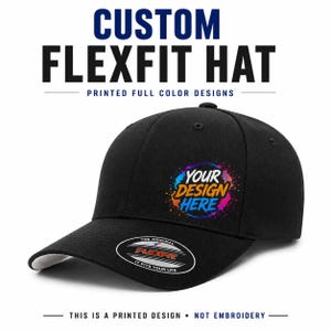 May include: A black Flexfit hat featuring a circular graphic with colourful paint splatters and the text YOUR DESIGN HERE. The brim displays a black and white sticker with the text THE ORIGINAL FLEXFIT IT FITS YOUR LIFE.