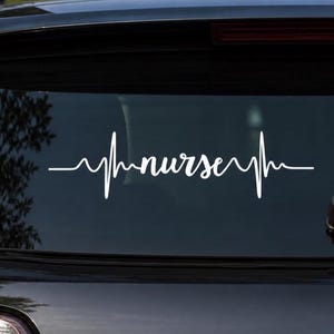 May include: White vinyl decal of a heartbeat line with the word "nurse" in cursive script. The decal is applied to the rear window of a black vehicle. The design is a symbol of the nursing profession.
