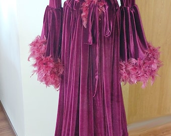 May include: A long, burgundy velvet robe with a large, fluffy feather collar and cuffs. The robe has a sash tie at the waist and a pearl necklace.