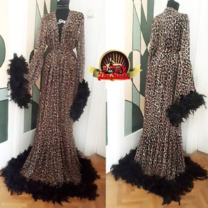 May include: A long leopard print robe with black feather trim around the cuffs, hem, and collar.