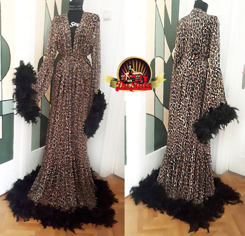 May include: A long leopard print robe with black feather trim around the cuffs, hem, and collar.