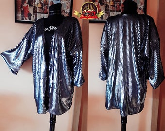 May include: A silver sequined kimono with a long, open front and three-quarter sleeves. The kimono has a subtle striped pattern and is made of a soft, flowing fabric.