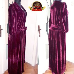 May include: A long, burgundy velvet robe with a tie belt. The robe has long sleeves and a V-neckline.