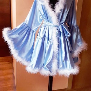 May include: A light blue satin robe with white feather trim. The robe has a ruffled hem and a sash tie.