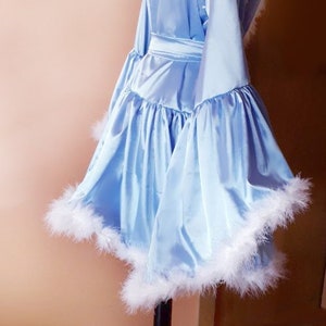 May include: A light blue satin robe with white feather trim. The robe has a sash and a ruffled hem.