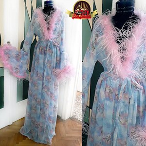 Puede incluir: Una bata de gasa azul claro con ribete de plumas rosas. La bata tiene un lazo en la cintura y mangas largas. La bata est&aacute; decorada con un estampado de unicornio pastel.
