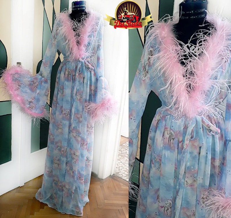 Puede incluir: Una bata de gasa azul claro con ribete de plumas rosas. La bata tiene un lazo en la cintura y mangas largas. La bata est&aacute; decorada con un estampado de unicornio pastel.