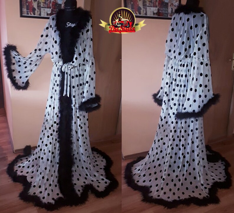 May include: White sheer robe with black polka dots and black feather trim. The robe has a long, flowing silhouette and a tie at the waist.