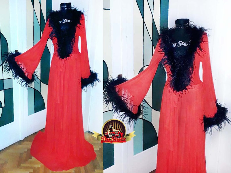 Puede incluir: Una larga bata roja transparente con ribete de plumas negras alrededor del cuello, las mangas y la faja. La bata est&aacute; hecha de una tela ligera y fluida.