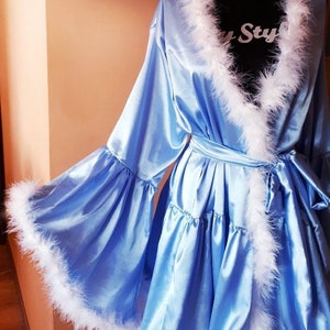 May include: A light blue satin robe with white feather trim around the neckline, sleeves, and hem. The robe has a tie belt and a ruffled skirt.