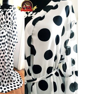 May include: A white sheer robe with black polka dots and a tie belt. The robe has long sleeves and a flowing skirt.