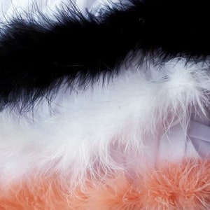 May include: Three strips of feather trim in black, white, and peach colors. The feather trim is soft and fluffy.