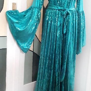 May include: A long turquoise sequined robe with a tie belt and long bell sleeves.