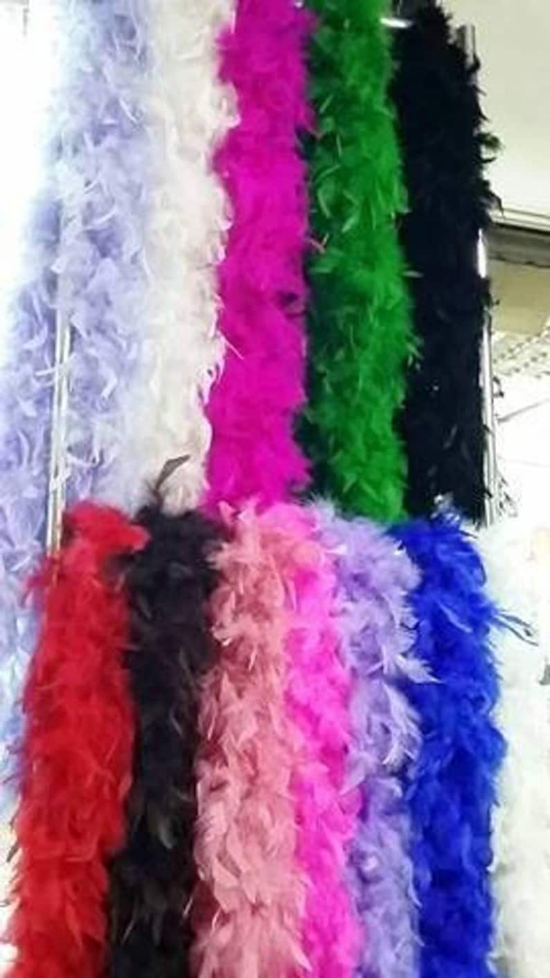 May include: Assortment of colorful feather boas in various colors, including red, pink, purple, black, white, and green. The boas are arranged vertically in a row.