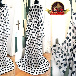 May include: A white sheer maxi dress with black polka dots and long sleeves. The dress has a V-neckline and a tie belt at the waist.