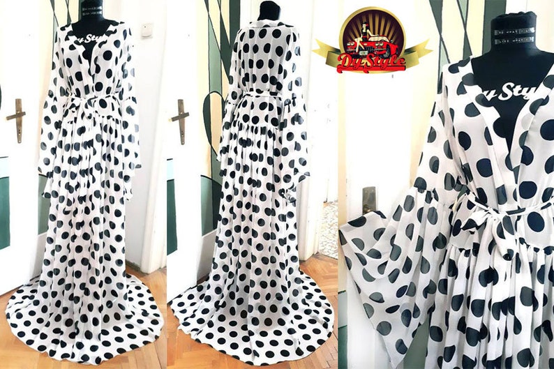 May include: A white sheer maxi dress with black polka dots and long sleeves. The dress has a V-neckline and a tie belt at the waist.