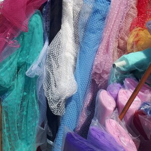 May include: Assortment of colorful tulle fabric rolls with polka dot patterns in various colors, including pink, blue, green, white, and purple.