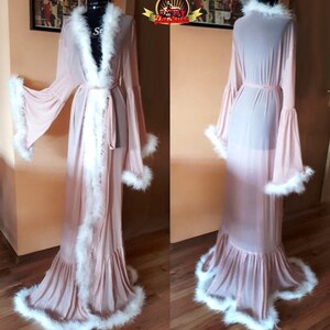 May include: A long, sheer pink robe with white feather trim. The robe has a tie at the waist and long sleeves. The robe is shown from the front and back.