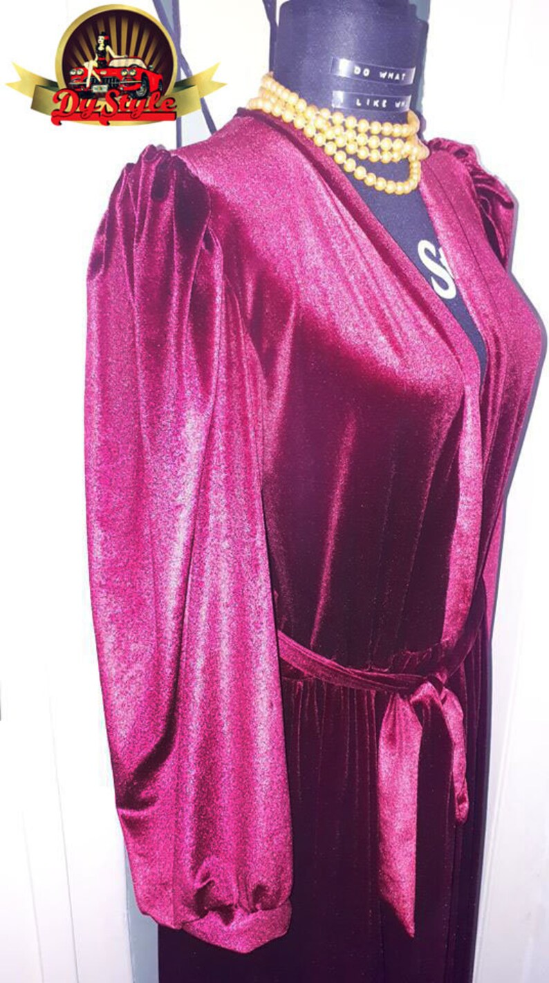 May include: A long-sleeved, burgundy velvet robe with a tie belt. The robe has puffed sleeves and a V-neckline.