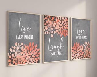 May include: Three framed prints with gray backgrounds and coral floral designs. The prints feature the words "Live Every Moment", "Laugh Every Day", and "Love Beyond Words".