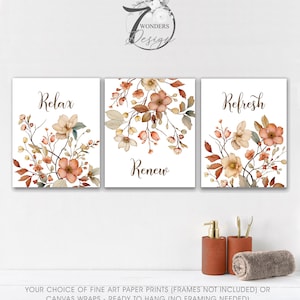 May include: Three framed floral art prints with the words "Relax", "Renew", and "Refresh". The prints feature watercolor flowers in shades of peach, brown, and green. The artwork is displayed on a white background.