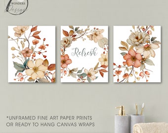 May include: A set of three floral art prints featuring watercolor flowers in shades of peach, cream, and brown. The center print has the word "Refresh" in script. The prints are on a white background.