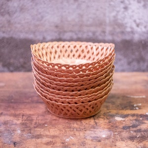 May include: A stack of woven wicker baskets in a light brown color. The baskets are round and have a woven pattern.