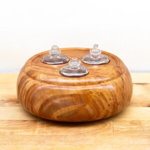 May include: A wooden bowl with three clear glass inserts. The bowl is made of a light brown wood with visible grain patterns. The glass inserts have a small, rounded shape.