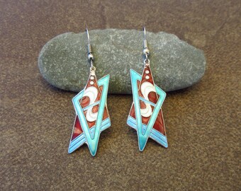 May include: A pair of silver dangle earrings with a geometric design. The earrings are red, blue, and white with a swirl pattern.