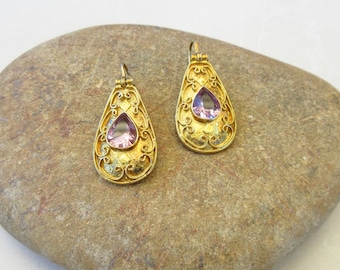 May include: A pair of gold filigree earrings with teardrop-shaped pink stones.