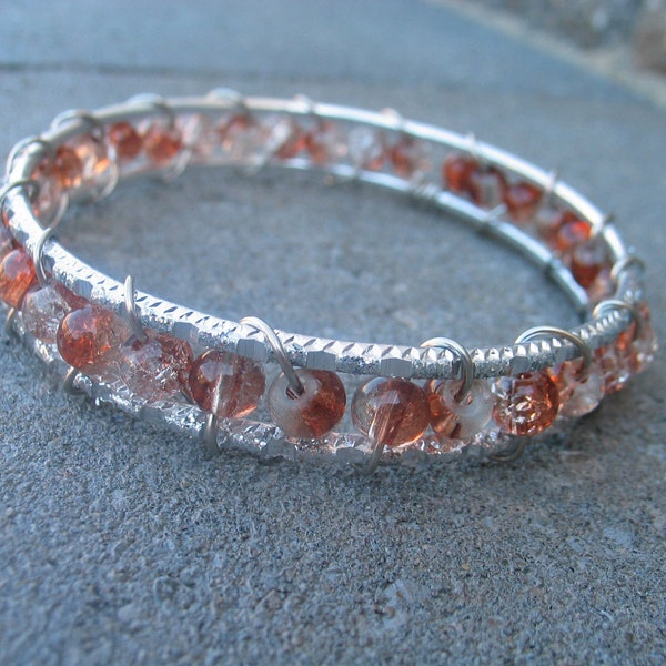 Wire wrapped bangle silver colored bracelet with clear white and brown frosted beads.