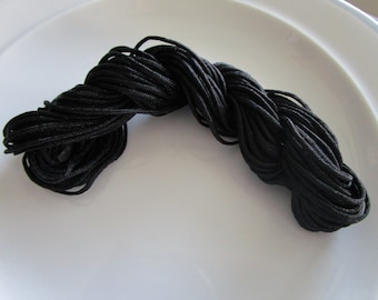 May include: A close-up of a spool of black cord. The cord is tightly wound and appears to be made of a durable material.