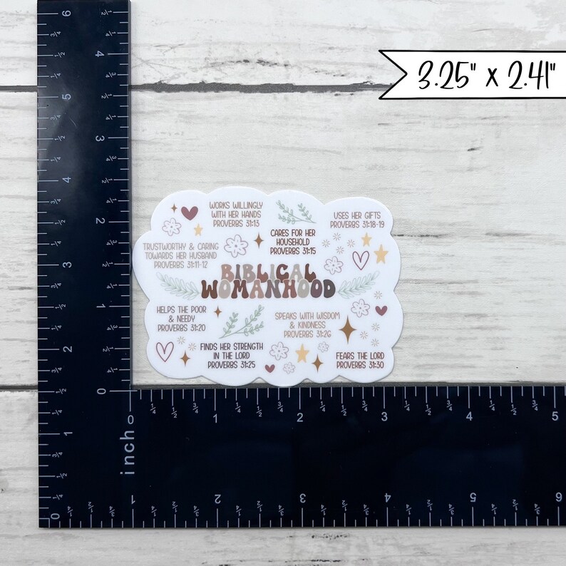 May include: A white sticker with a brown, beige, and pink floral design. The sticker features the text "Biblical Womanhood" with various Bible verses related to women. The sticker measures 3.25 inches by 2.41 inches.