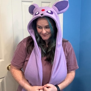 May include: A lavender fleece hood with large purple ears and a red dot on the forehead. The hood has long scarf-like extensions. The hood is designed to resemble a character from a popular animated series.