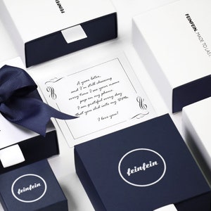 May include: A white box with a blue ribbon and a note inside that reads "A year later, and I'm still choosing every time I see your name pop on my phone. I am grateful every day that you slid into my DMs. I love you!" The box is labeled "feinfein" and "FEINFEIN. MADE TO LAST."