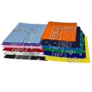 May include: A collection of bandanas in a range of colours, such as blue, orange, and green. Each square bandana displays a paisley pattern in a contrasting colour. They are made from a lightweight fabric.