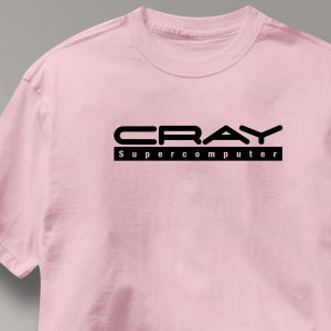 May include: A light pink t-shirt with the word "CRAY" in a bold, black, sans-serif font above the words "SUPERCOMPUTER" in a black, sans-serif font. The text is centered on the shirt.