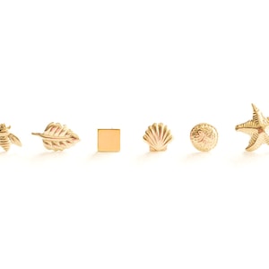 May include: A set of six gold-toned earrings featuring various designs, including a bee, a leaf, a square, a seashell, a sea urchin, and a starfish.