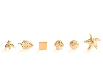 May include: A set of six gold-toned earrings featuring various designs, including a bee, a leaf, a square, a seashell, a sea urchin, and a starfish.