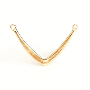 Puede incluir: Pendiente en forma de V de metal dorado con dos bucles en la parte superior.